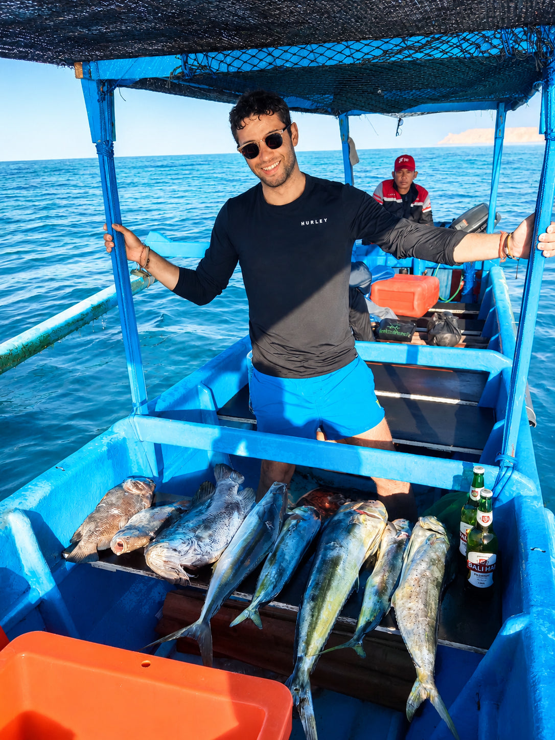 Man on a spearfishing charter in Bali with a spread of freshly speared pelagic fish displayed on the deck