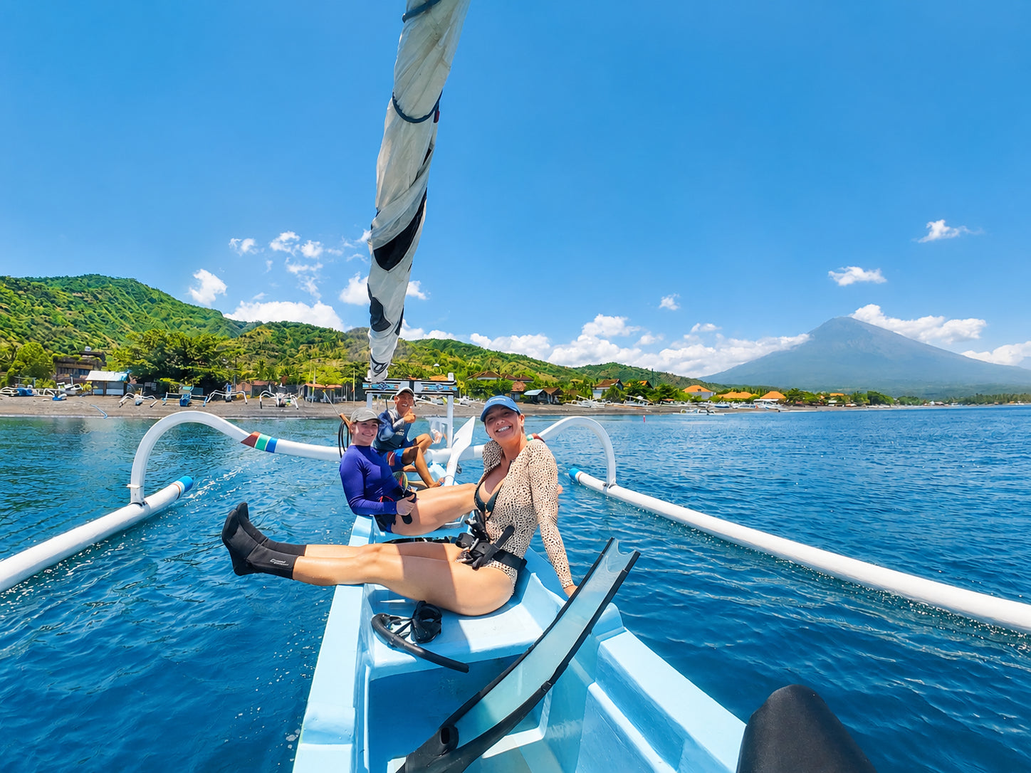 Two girls sitting on a local Balinese jukung boat with volcanoe Agung in the background