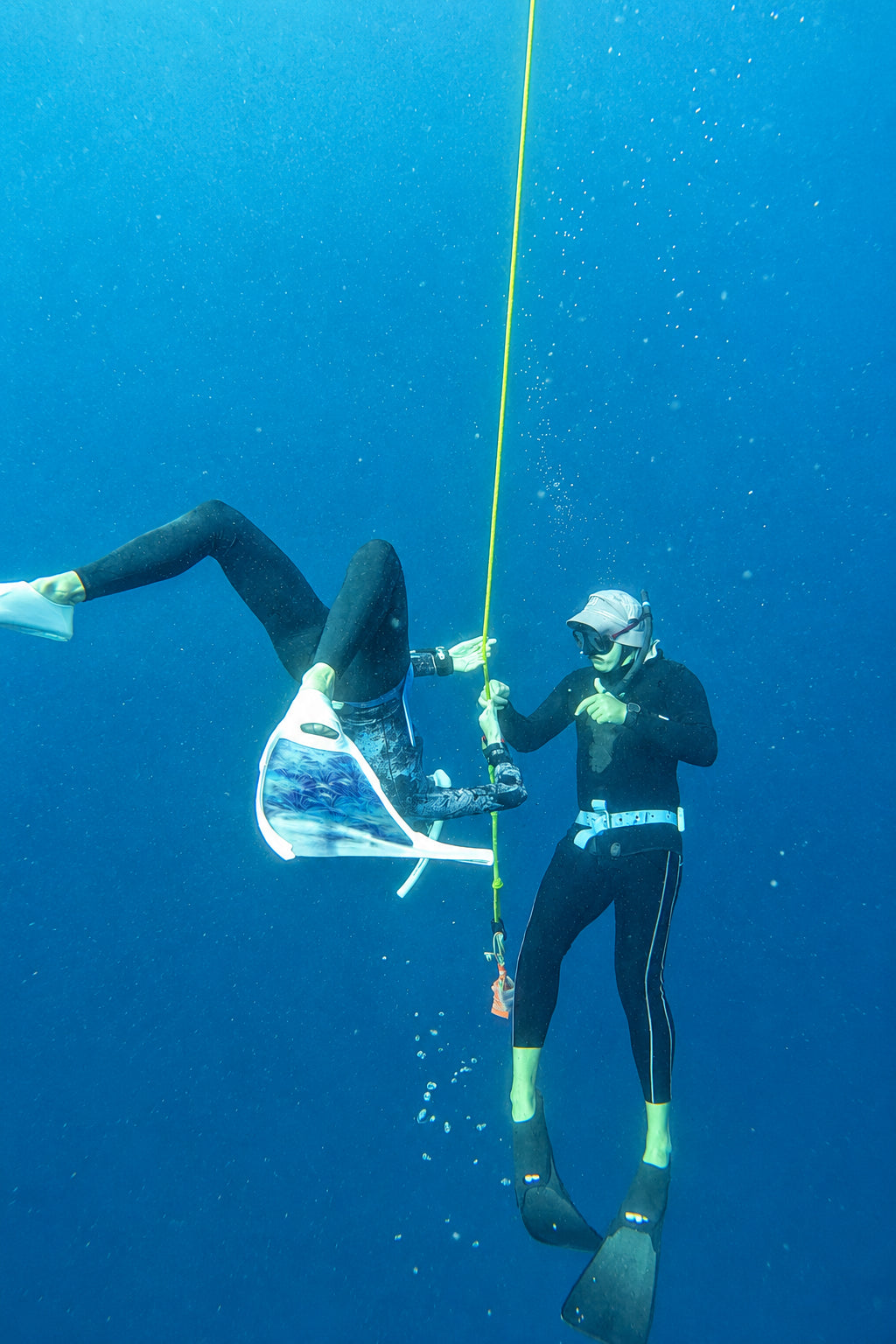 A student and a instructor underwater freediving on a line while practicing bottom turn skill